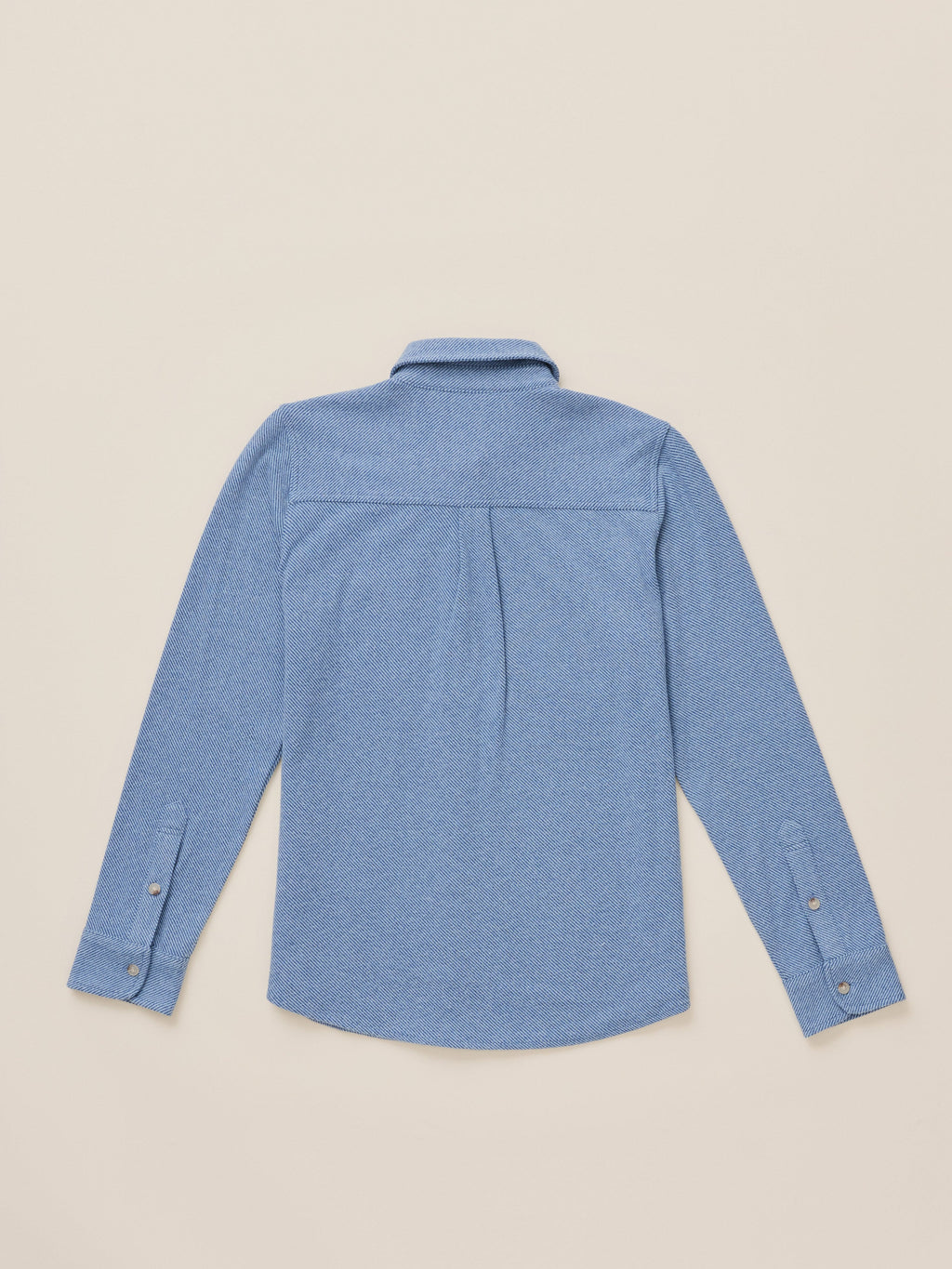 A light blue long-sleeve button-up shirt shown from the back, laid flat on a warm beige background.
