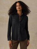 Woman wearing a black sweater shirt with brown striped pants against a beige background