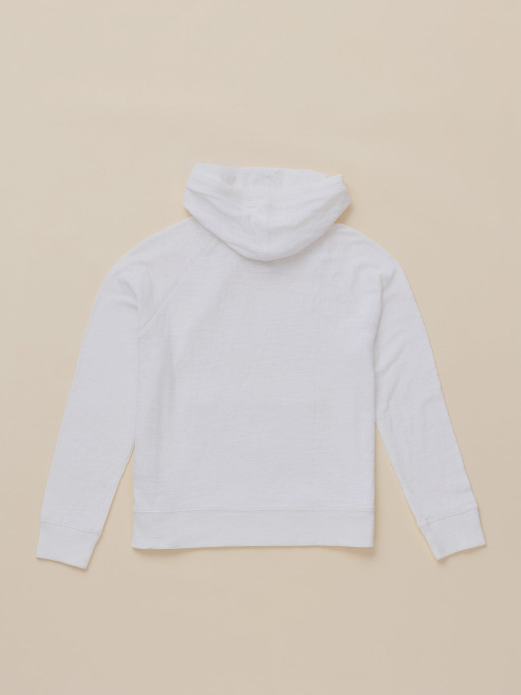 A white long-sleeve hoodie shown from the back, laid flat on a solid beige background.